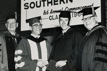 archival image of four men posing in graduation regalia