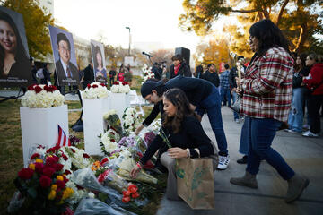 mourners laying flowers in front of photos at vigil